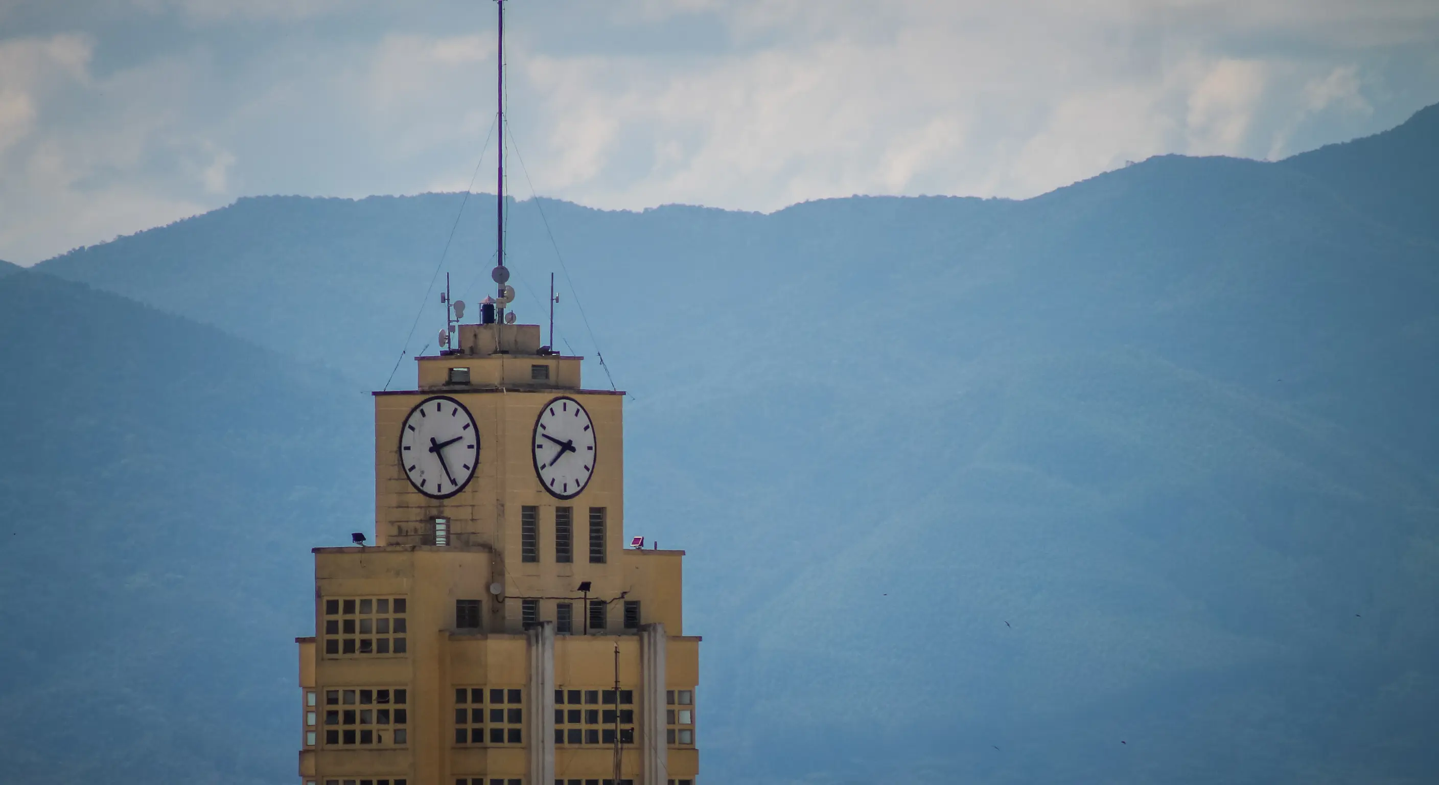 Vista marcante de Taubaté com torre de relógio em destaque, cercada por montanhas ao fundo, transmitindo charme urbano, tranquilidade e a beleza natural típica do interior paulista.