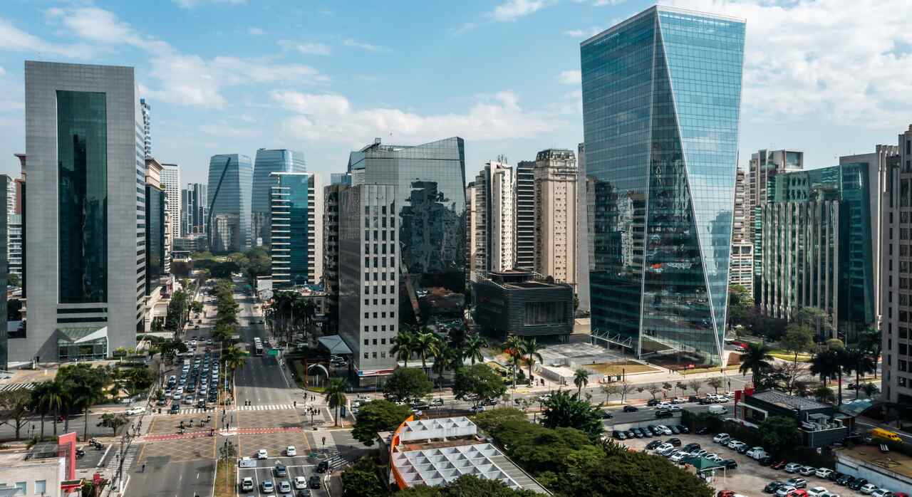 Avenida Paulista vista de cima, com prédios e carros passando.