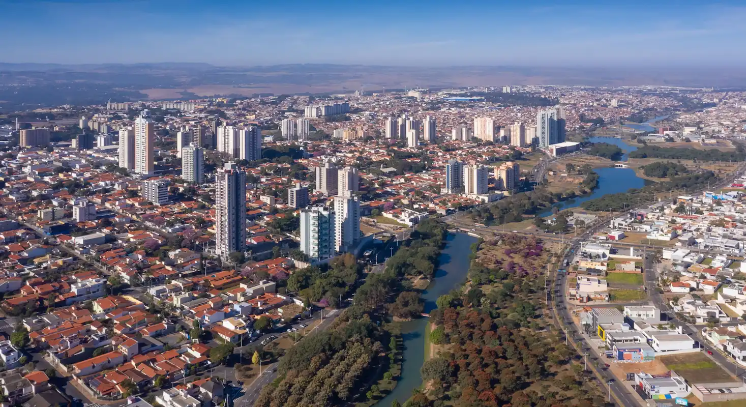 Vista aérea de Indaiatuba, com passagem pelo Rio Tietê, podendo serem vistos também alguns prédios e espaços arborizados.