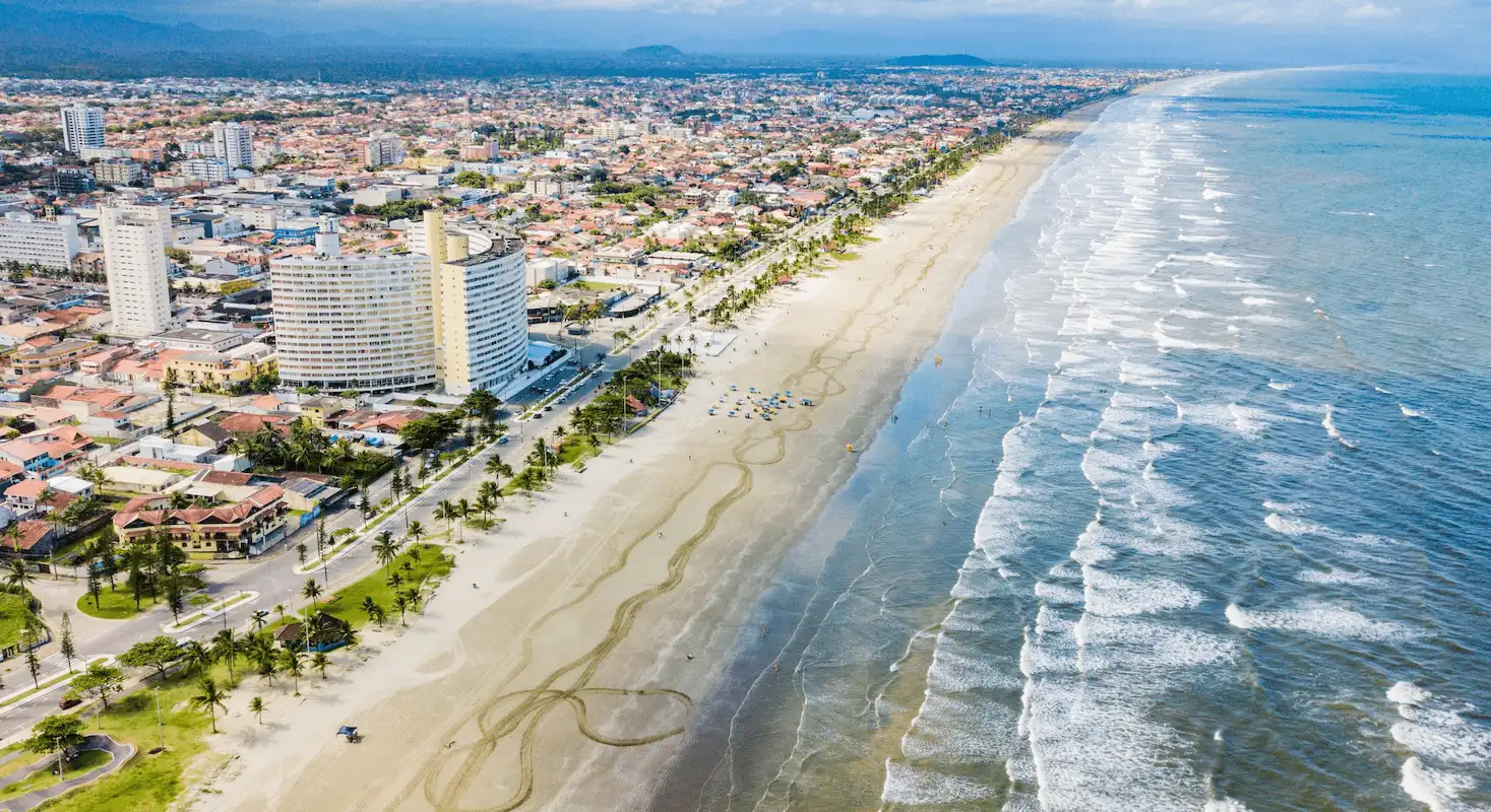 Peruíbe vista de cima, mostrando sua praia, faixa de areia e área residencial num dia claro.