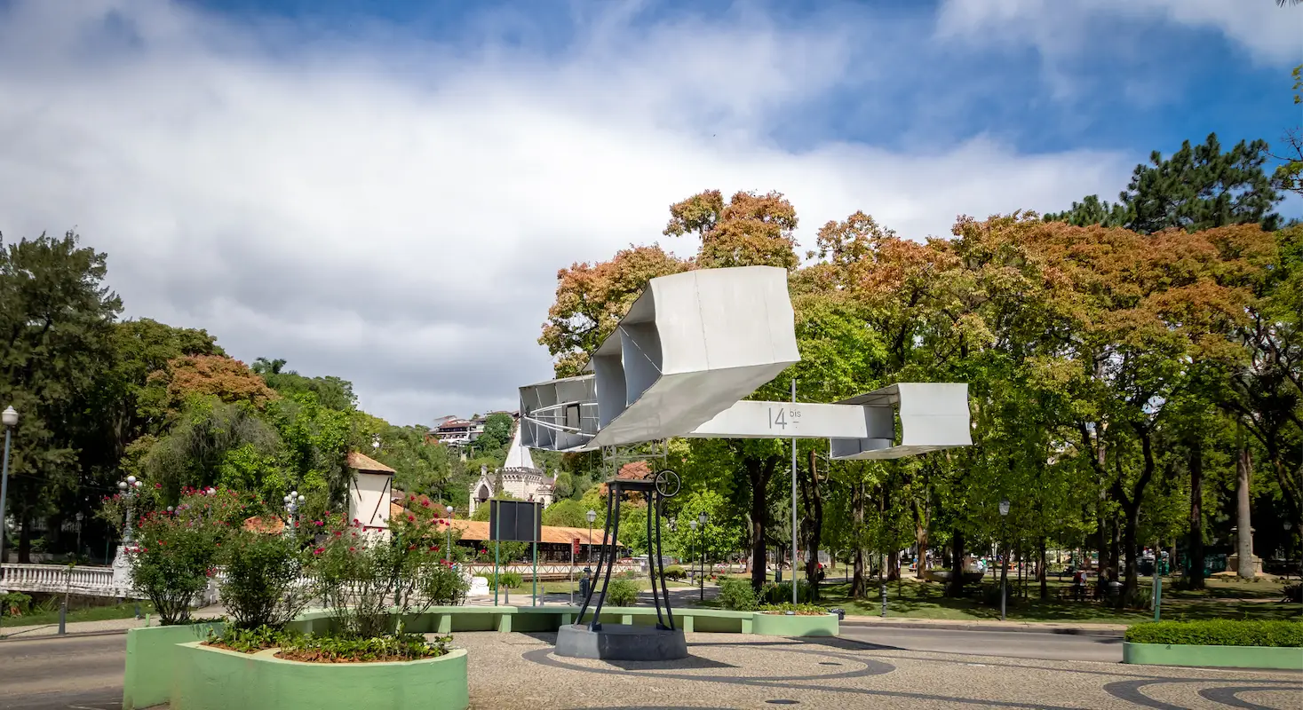 Vista arborizada de Petrópolis com monumento histórico, céu aberto e áreas verdes em ambiente tranquilo urbano.