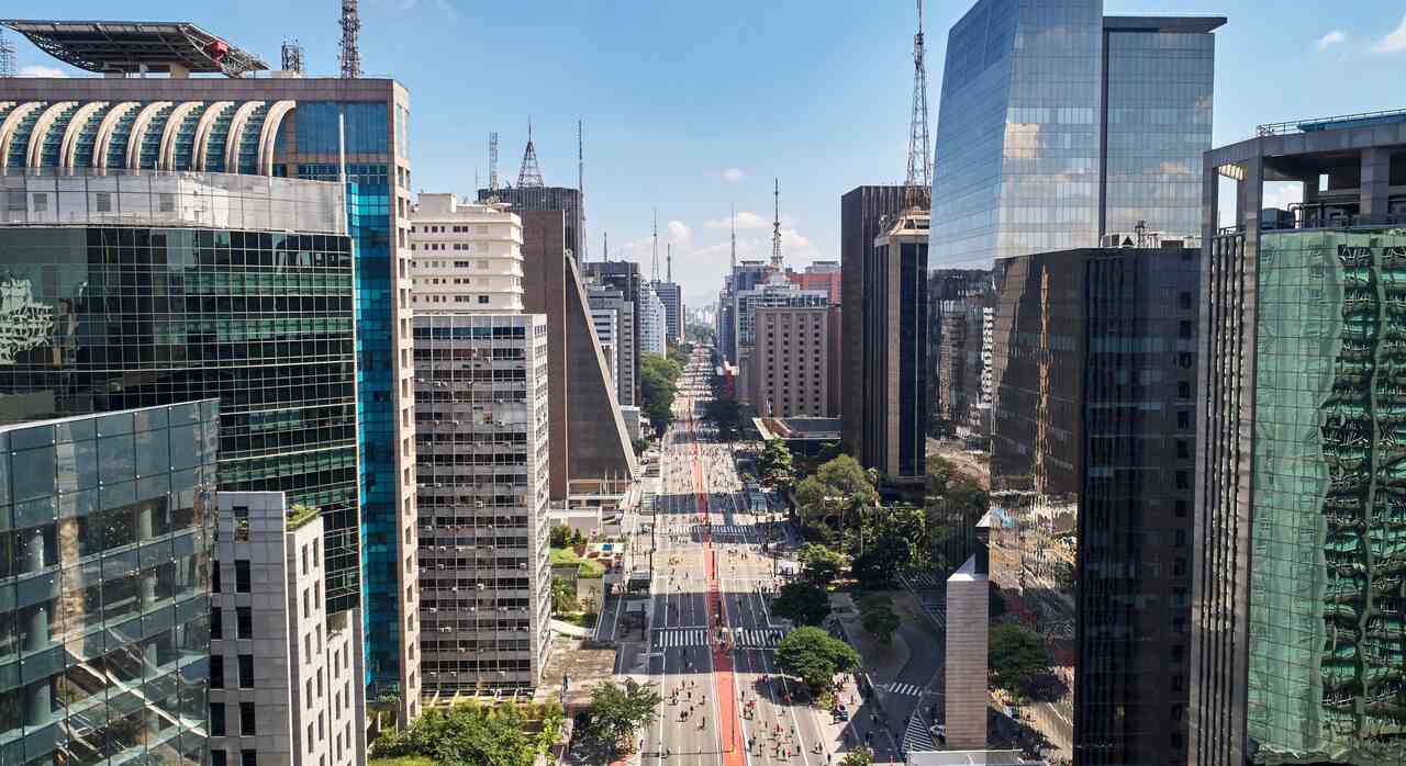 Avenida Paulista vista de cima, com prédios e carros passando.