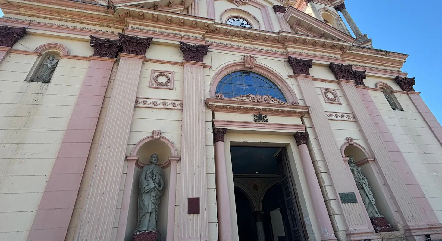 Fachada histórica da basílica em Tremembé destaca arquitetura clássica, colunas ornamentadas e entrada principal sob céu azul.